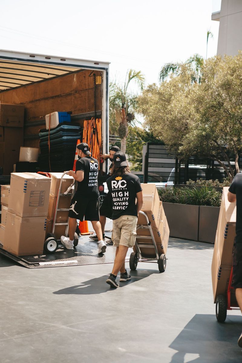 Loading crew wheeling cartons into a truck on a trolley